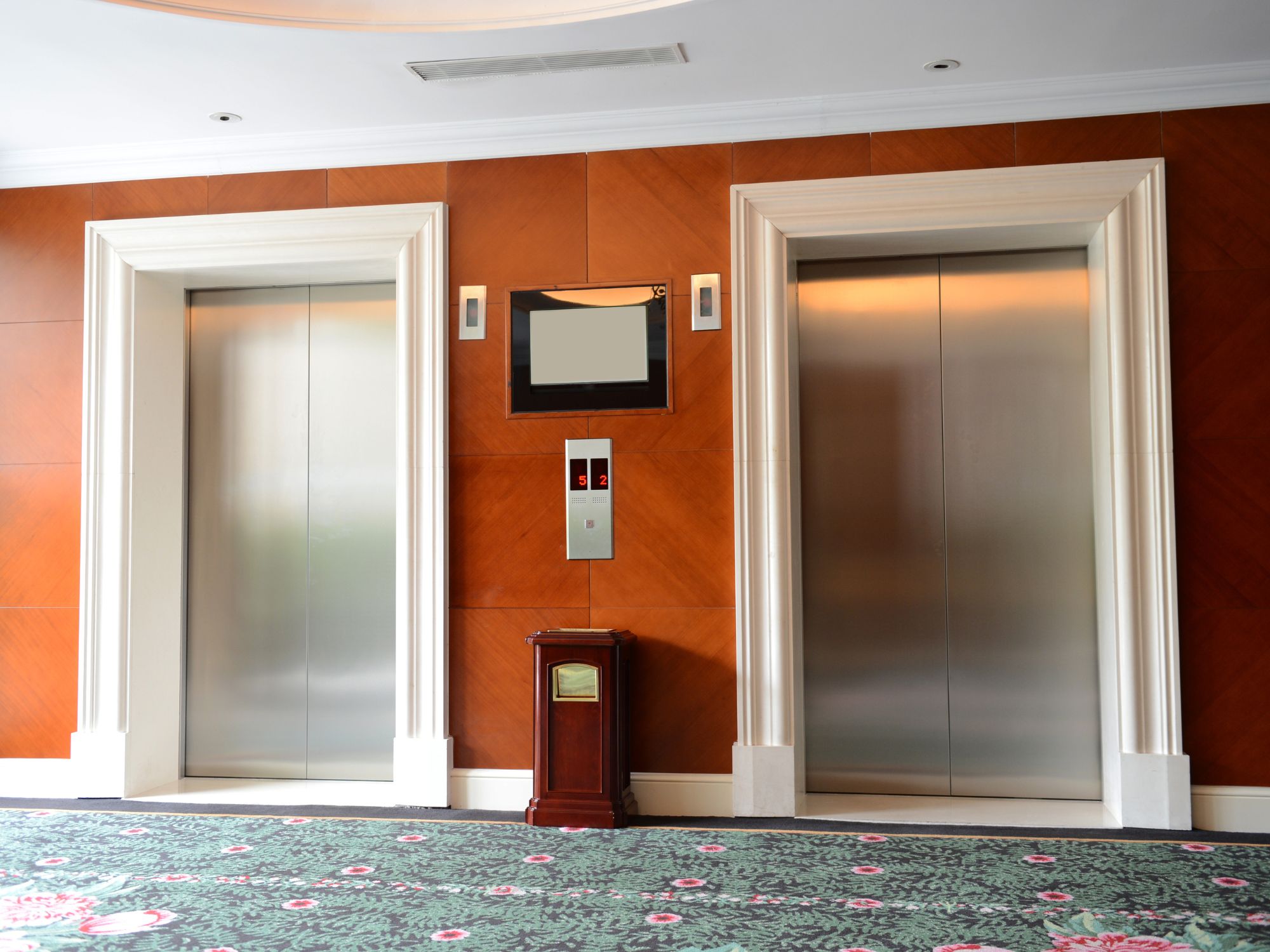 Closed elevator doors in a wood-paneled building lobby.