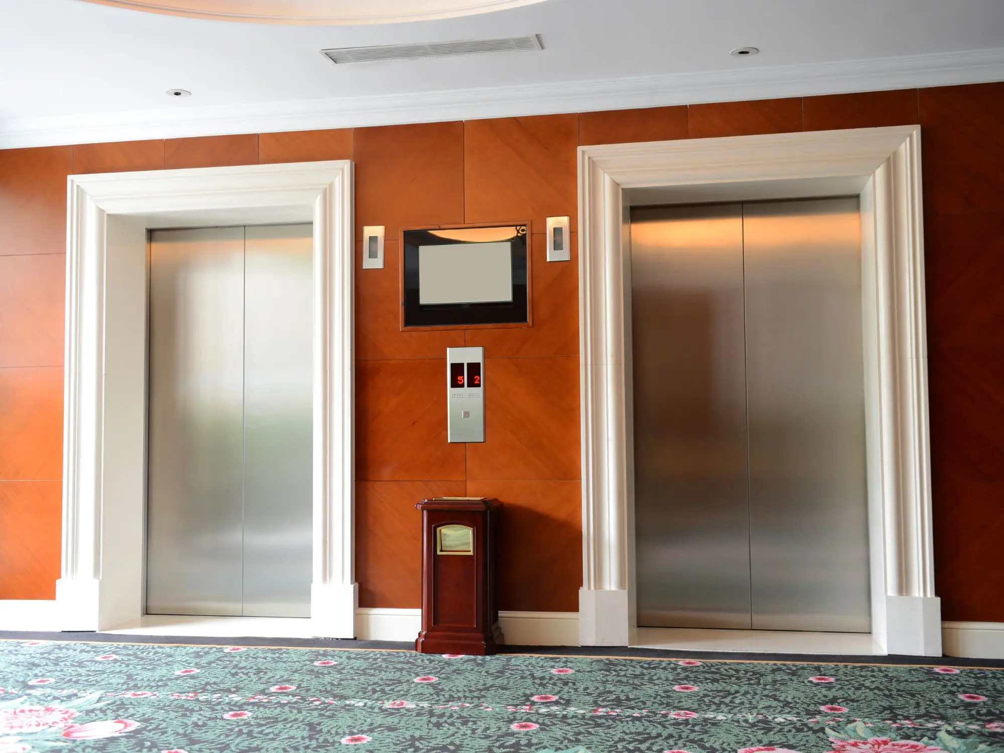 Closed elevator doors in a wood-paneled building lobby.