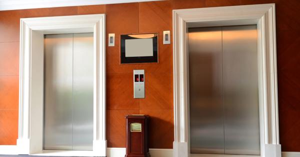 Closed elevator doors in a wood-paneled building lobby.