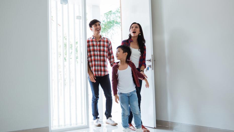 Family entering a bright, empty home through an open front door, stepping onto a polished floor. Family entering a bright, empty home through an open front door, stepping onto a polished floor.