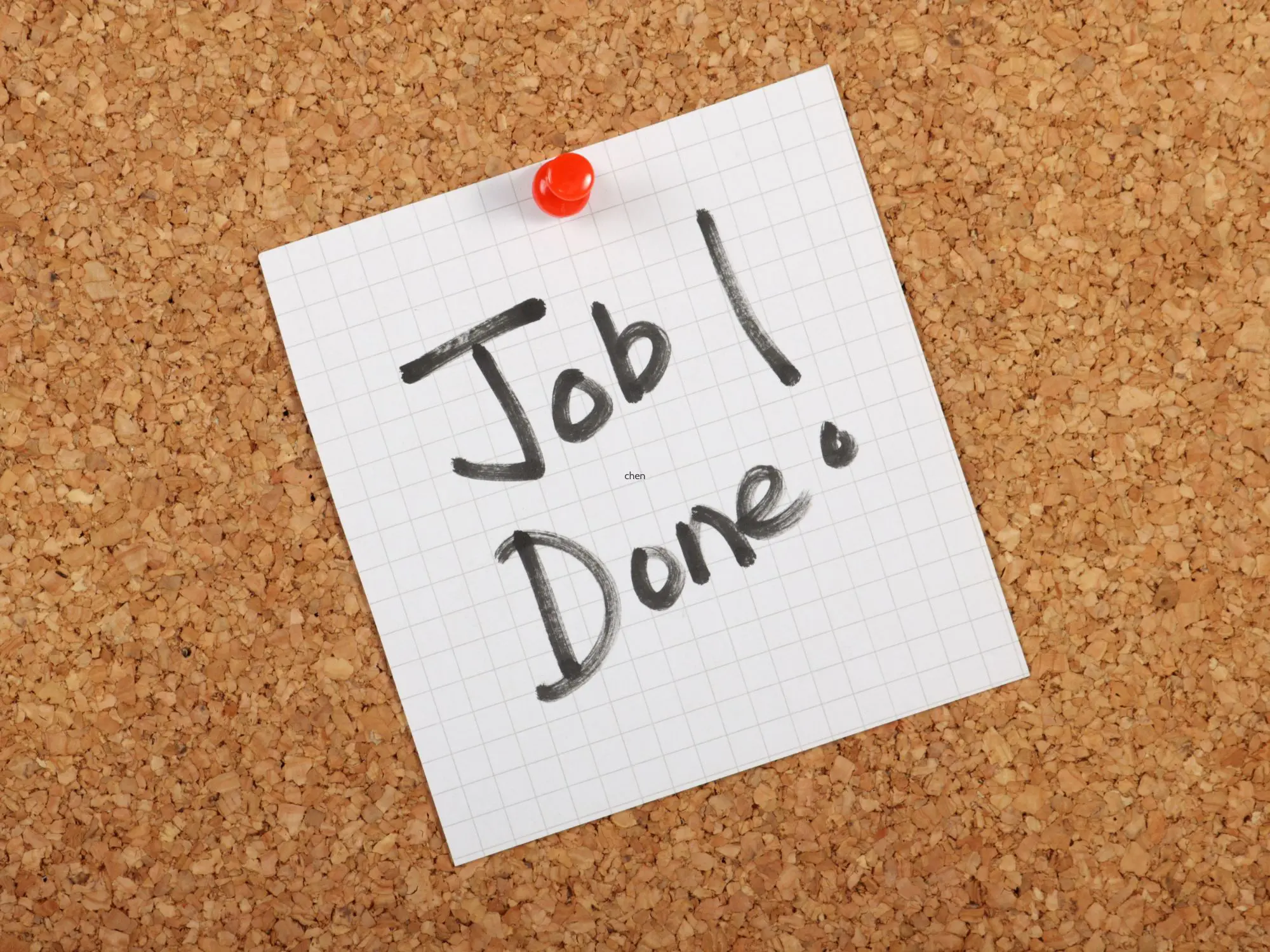Graph paper pinned to a corkboard with a red pushpin, displaying the handwritten message 'Job! Done.' in black marker