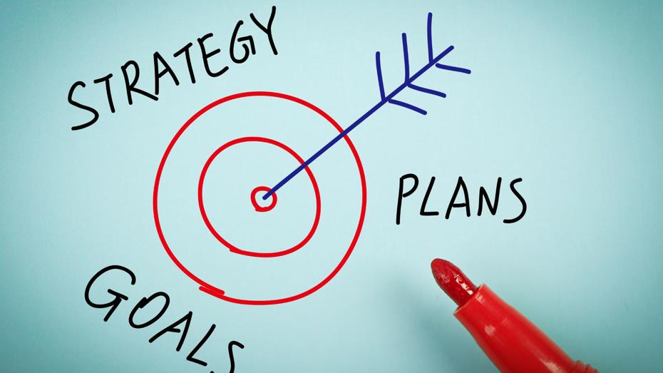 A red marker draws a target with an arrow hitting the bullseye, surrounded by the words "STRATEGY," "GOALS," and "PLANS," symbolizing the alignment of planning and strategy to achieve objectives. A red marker draws a target with an arrow hitting the bullseye, surrounded by the words "STRATEGY," "GOALS," and "PLANS," symbolizing the alignment of planning and strategy to achieve objectives.