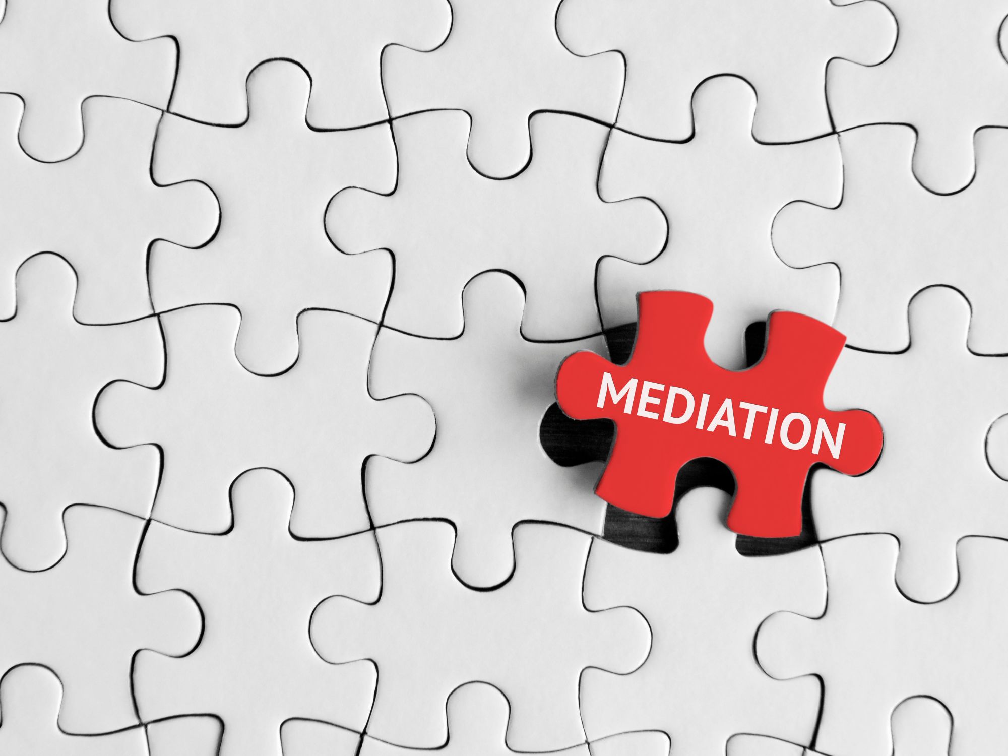 Red jigsaw puzzle piece labelled “MEDIATION” placed over a white puzzle with one piece missing, symbolising resolution and fitting solutions in community conflict.
