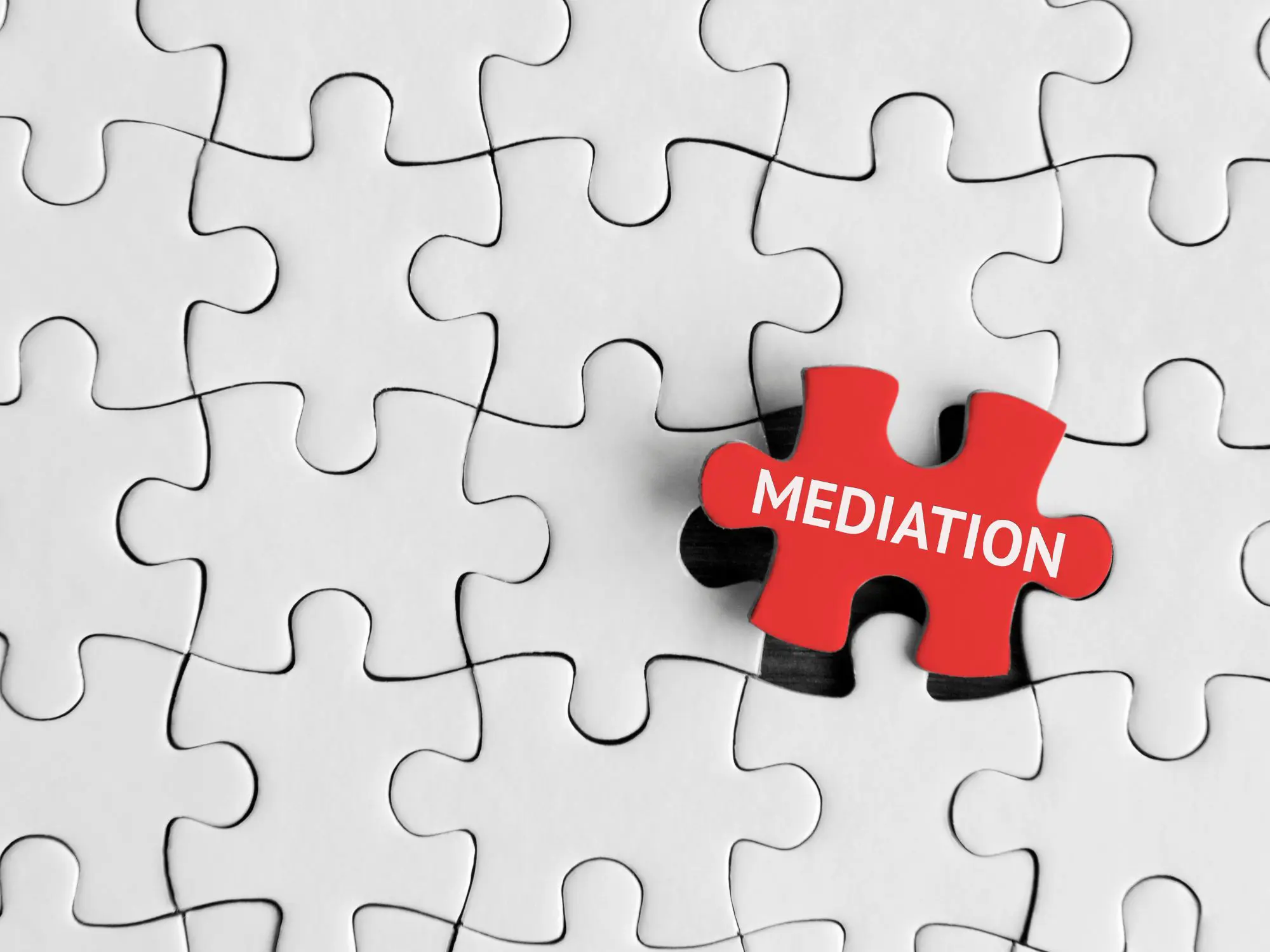 Red jigsaw puzzle piece labelled “MEDIATION” placed over a white puzzle with one piece missing, symbolising resolution and fitting solutions in community conflict.