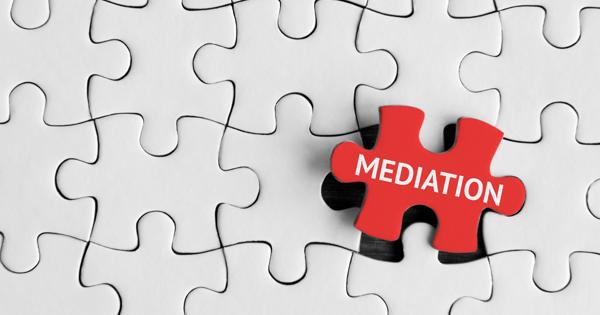 Red jigsaw puzzle piece labelled “MEDIATION” placed over a white puzzle with one piece missing, symbolising resolution and fitting solutions in community conflict.