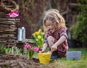 A child is sitting outdoors in a garden area, using a small trowel to dig soil near a yellow bucket. Pink hyacinth flowers are planted nearby, and gardening tools and plants can be seen in the background. On the left, a rounded text box says: “Got some spring planting questions? Come along to Grow Speke on Friday 10 April from 11am!” In the top right corner is The Big SLH Garden Competition logo, which includes a pink and purple fuchsia flower above the text.