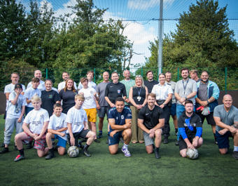 A group of young people and adults pose for a group shot before a football match.