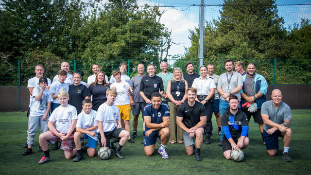 A group of young people and adults pose for a group shot before a football match.