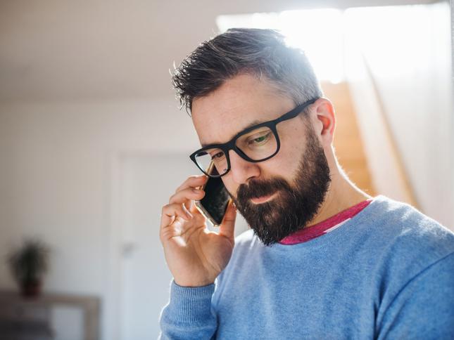 A person wearing glasses talking on the phone indoors. A person wearing glasses talking on the phone indoors.