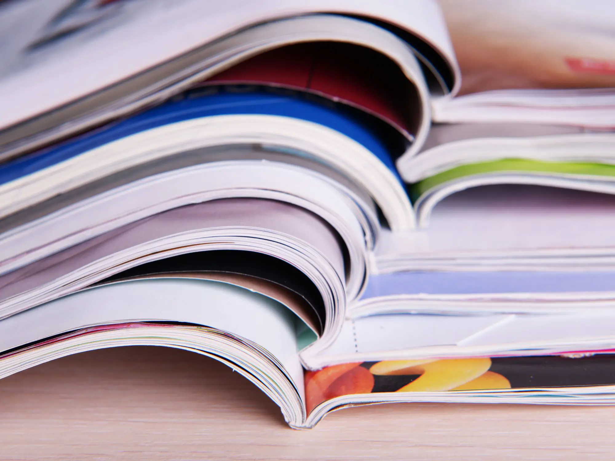 A stack of open magazines fanned out, showing colourful pages and covers, representing a collection of publications.