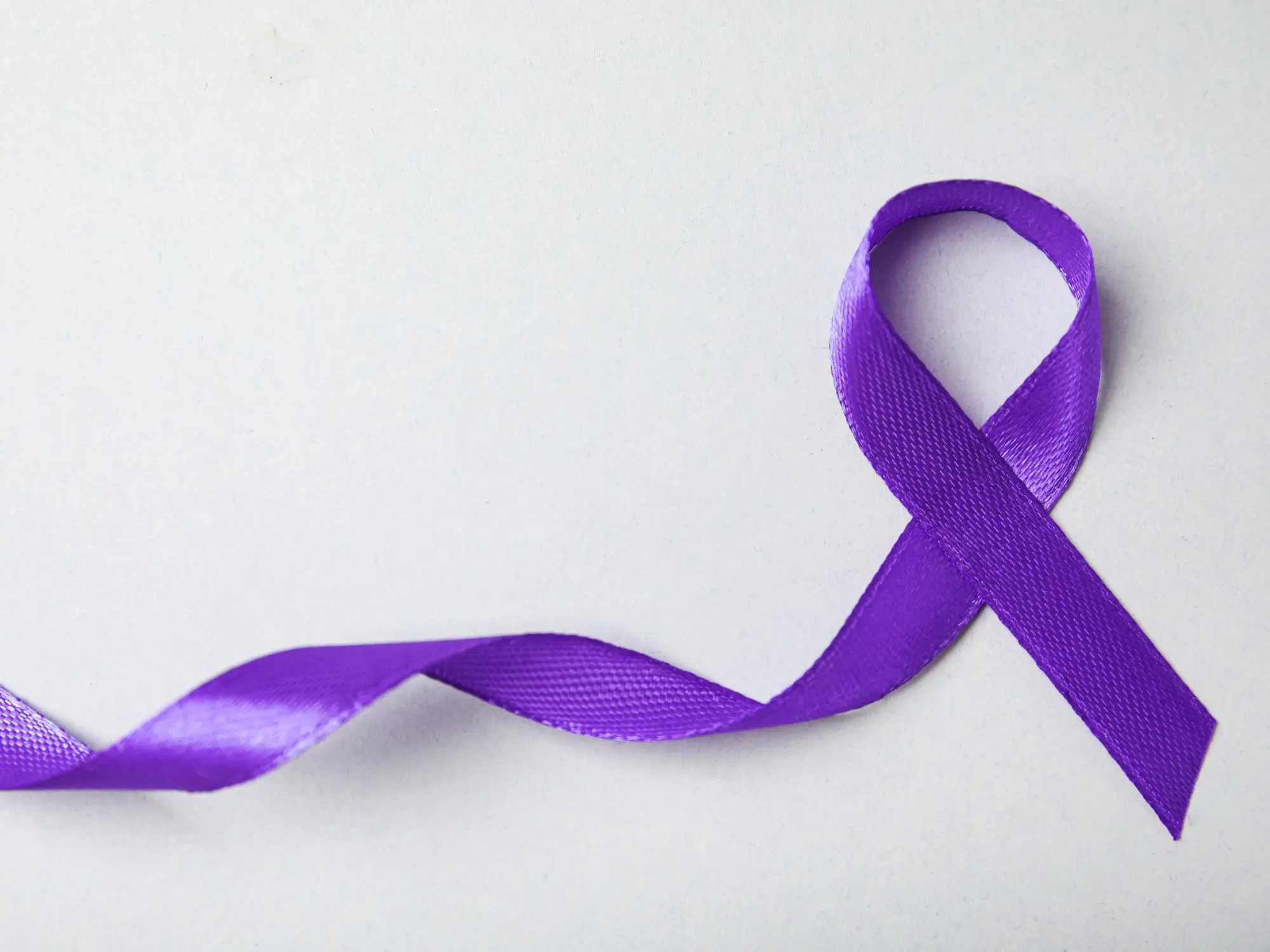 Purple awareness ribbon on a light background, symbolising support for domestic abuse survivors and raising awareness of domestic violence.