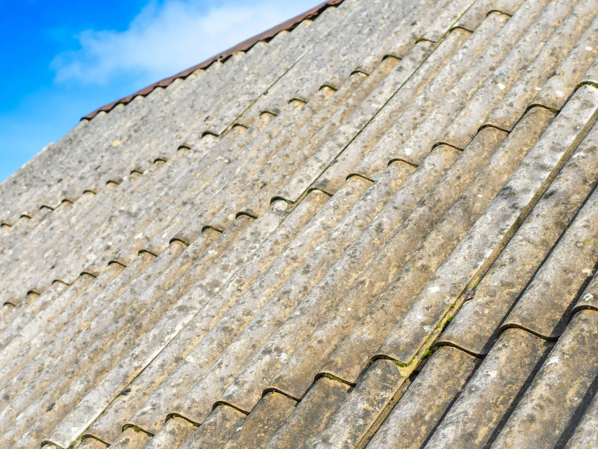 Old asbestos roof under a clear blue sky.