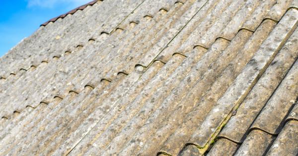 Old asbestos roof under a clear blue sky.