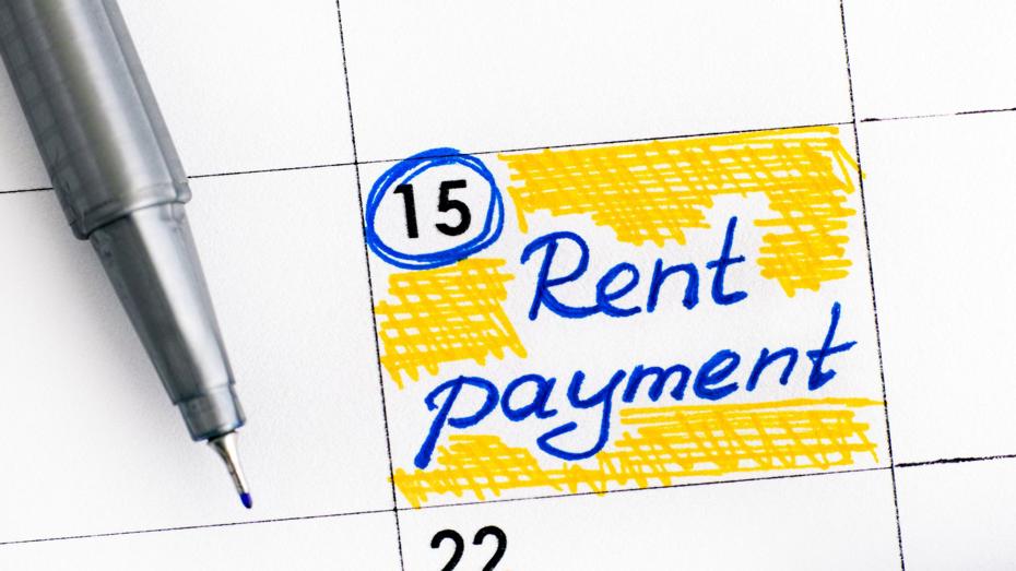 A close-up of a calendar page with the date 15 circled in blue and the words “Rent payment” written in blue ink on a yellow highlighted background. A pen is visible near the top left. A close-up of a calendar page with the date 15 circled in blue and the words “Rent payment” written in blue ink on a yellow highlighted background. A pen is visible near the top left.