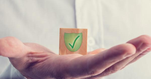 Open hand holding a wooden block with a green shield and checkmark, symbolising protection, trust, and safeguarding within the community.