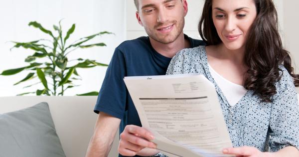 Two people sitting on a couch reviewing a document together, with a plant in the background and a grey cushion nearby.