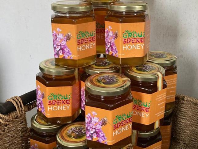 Stacked jars of 'Grow Speke Honey' with floral and bee-themed labels, showcasing locally produced honey. Stacked jars of 'Grow Speke Honey' with floral and bee-themed labels, showcasing locally produced honey.