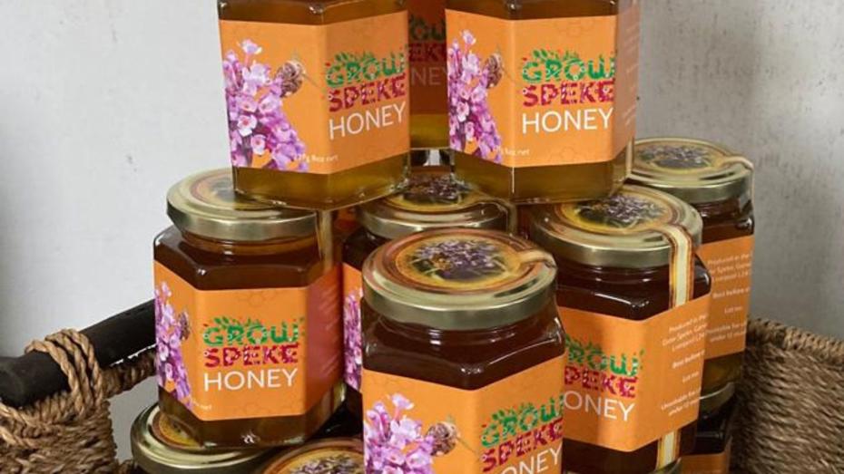 Stacked jars of 'Grow Speke Honey' with floral and bee-themed labels, showcasing locally produced honey. Stacked jars of 'Grow Speke Honey' with floral and bee-themed labels, showcasing locally produced honey.