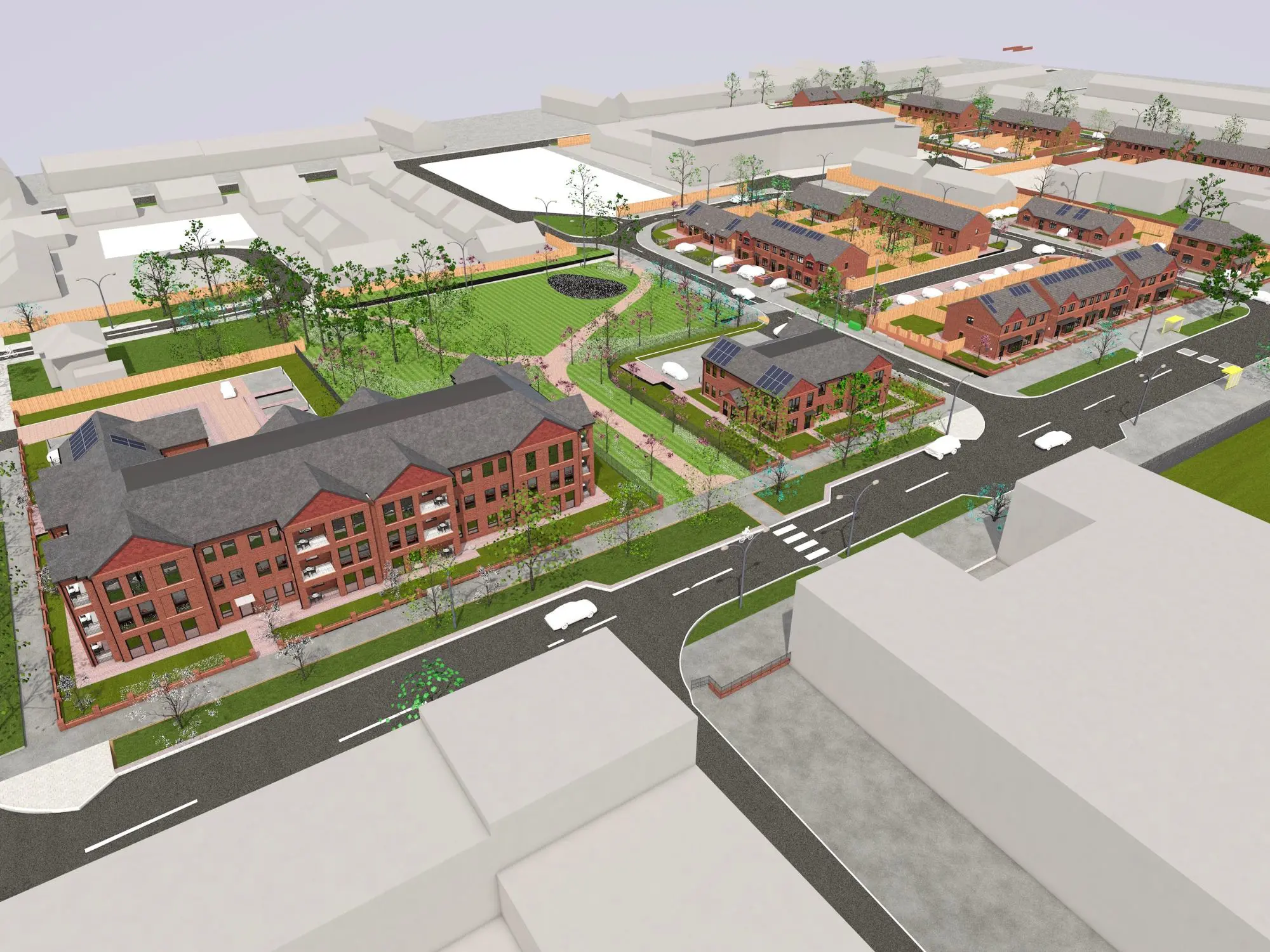 Aerial view of a planned residential development featuring red brick multi-story buildings, smaller homes with solar panels, organized streets, crosswalks, sidewalks, and landscaped green spaces with trees and grass.