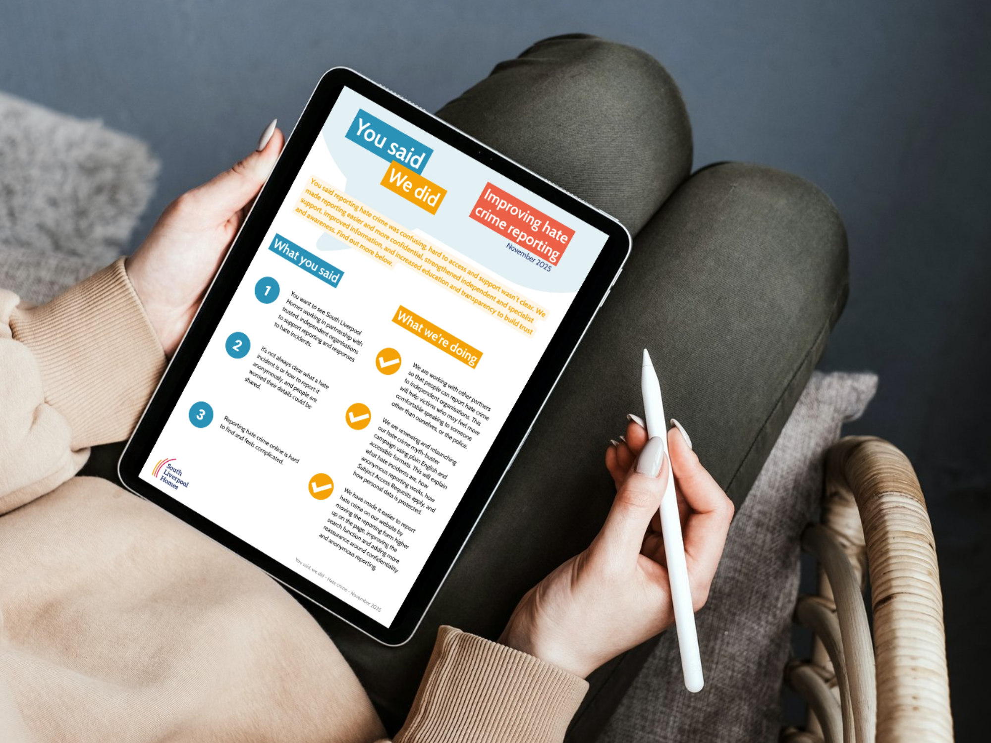 Person sitting with a tablet, holding a stylus pen, viewing a “You said, we did” update titled “Improving hate crime reporting” with sections outlining feedback and actions taken.