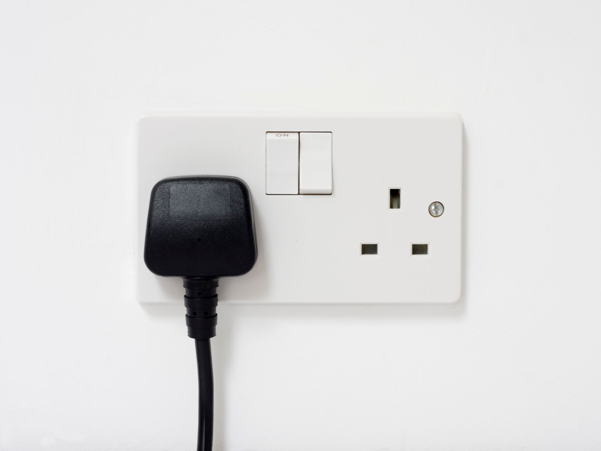 UK electrical outlet with a plug inserted and switches visible.
