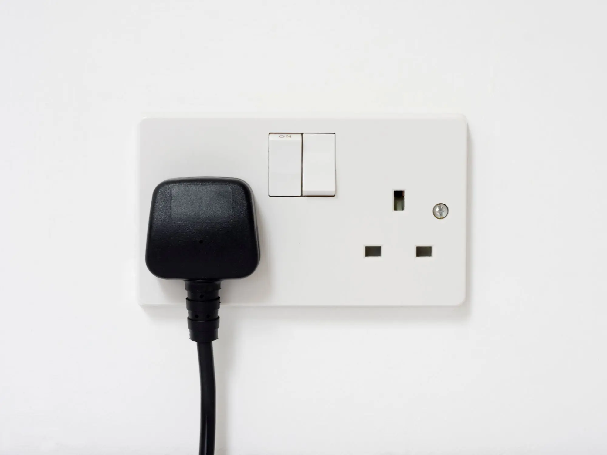 UK electrical outlet with a plug inserted and switches visible.