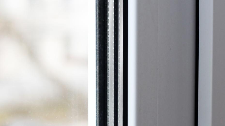 Close-up of a double-glazed window frame showing the seal and spacer between two glass panes, with a blurred outdoor background. Close-up of a double-glazed window frame showing the seal and spacer between two glass panes, with a blurred outdoor background.