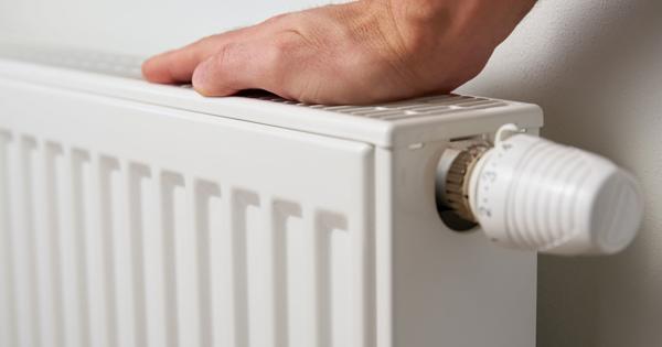 Hand resting on a white radiator with an adjustable thermostat knob on the side.