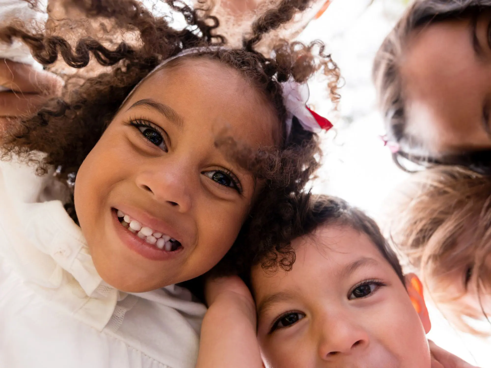 Four smiling children looking down at the camera, capturing a joyful moment of togetherness and play.