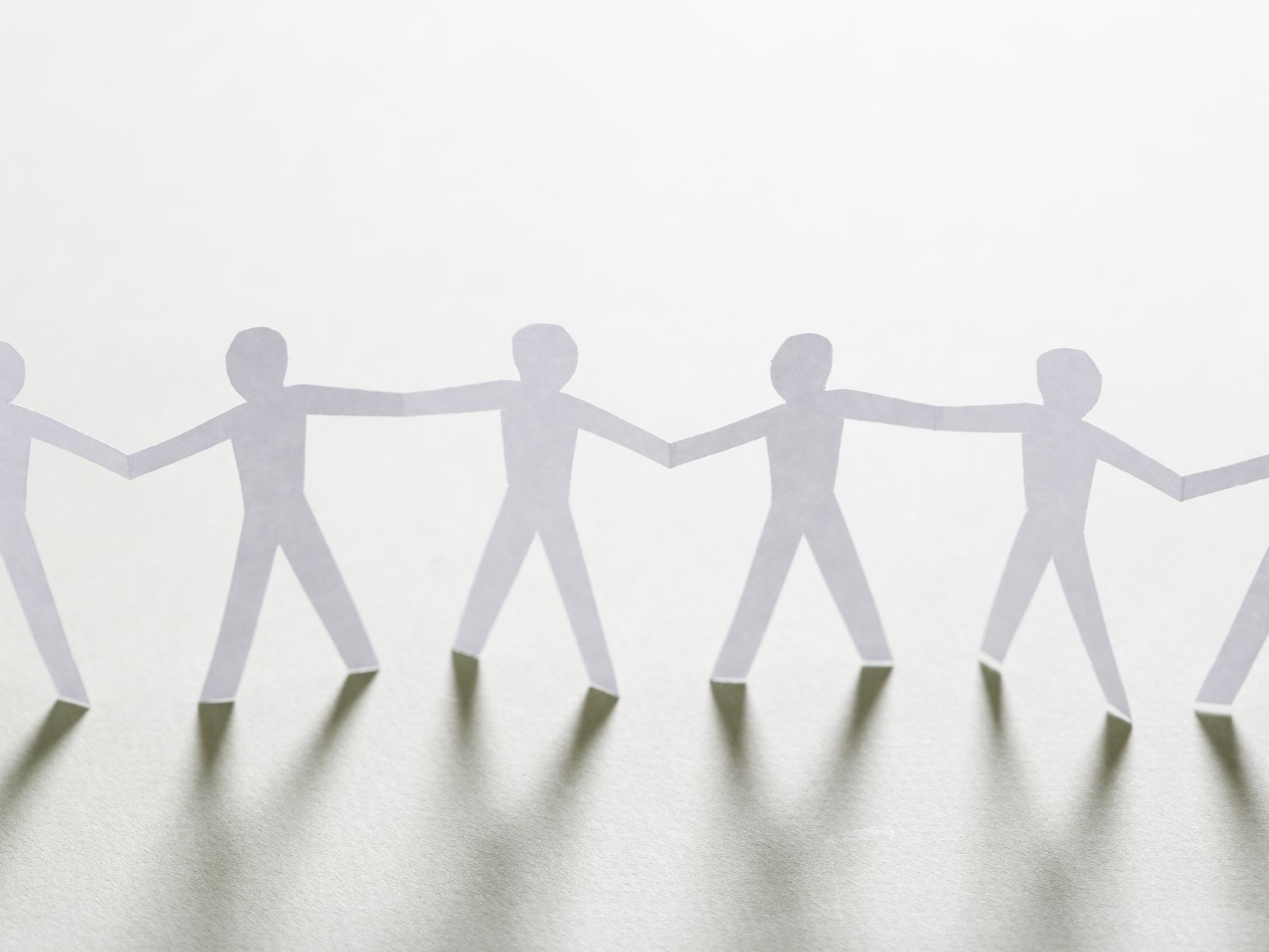 Paper cut-out figures holding hands in a chain, symbolising unity, collaboration, and community safety.