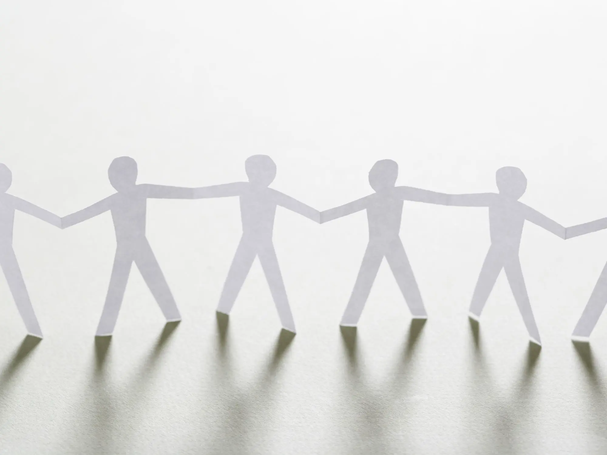 Paper cut-out figures holding hands in a chain, symbolising unity, collaboration, and community safety.