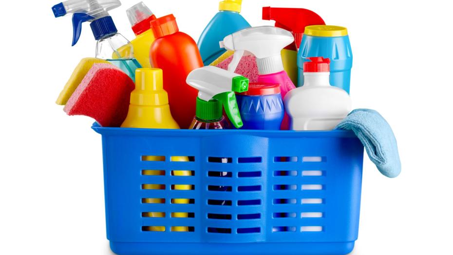 Blue plastic basket containing assorted cleaning supplies including spray bottles, sponges, liquid containers, and a cloth in various colours. Blue plastic basket containing assorted cleaning supplies including spray bottles, sponges, liquid containers, and a cloth in various colours.