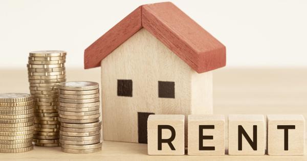A small wooden house with a red roof sits beside stacks of coins and wooden blocks spelling 'RENT'—symbolizing property rental and rising costs.