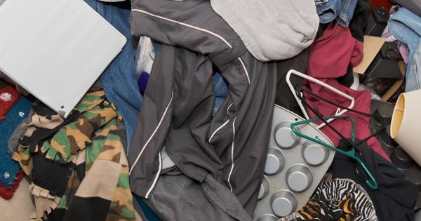 A cluttered pile of assorted items including clothes, hangers, and an electronic device, possibly a tablet.