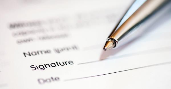 Close-up of a pen resting on a document with fields for name, signature, and date—representing the process of signing formal paperwork.