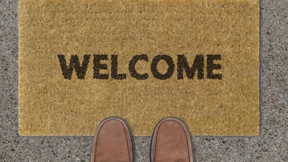 Brown doormat with the word 'WELCOME' in black letters, placed on a concrete surface with two brown shoes visible in front of it. Brown doormat with the word 'WELCOME' in black letters, placed on a concrete surface with two brown shoes visible in front of it.