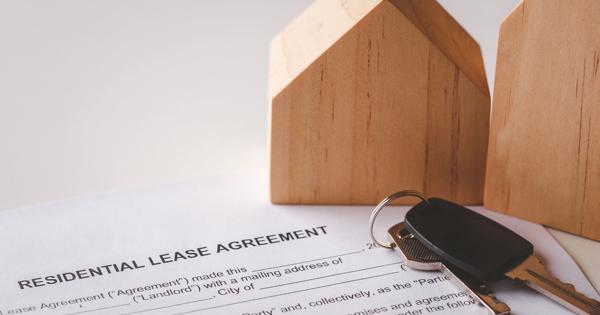 A residential lease agreement document with two wooden house models and a set of keys placed on top—symbolizing property rental and the legal aspects of tenancy.