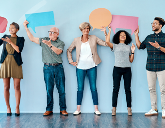 Five people stand in a row against a light blue background, each holding a colourful speech bubble above their head.
