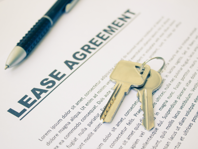 Keys resting on a lease agreement document, with a pen in the background.