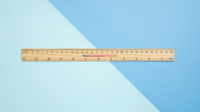 Wooden ruler with centimeter and inch markings placed diagonally on a two-tone blue background, featuring the text 'Tenant Satisfaction Measures'.