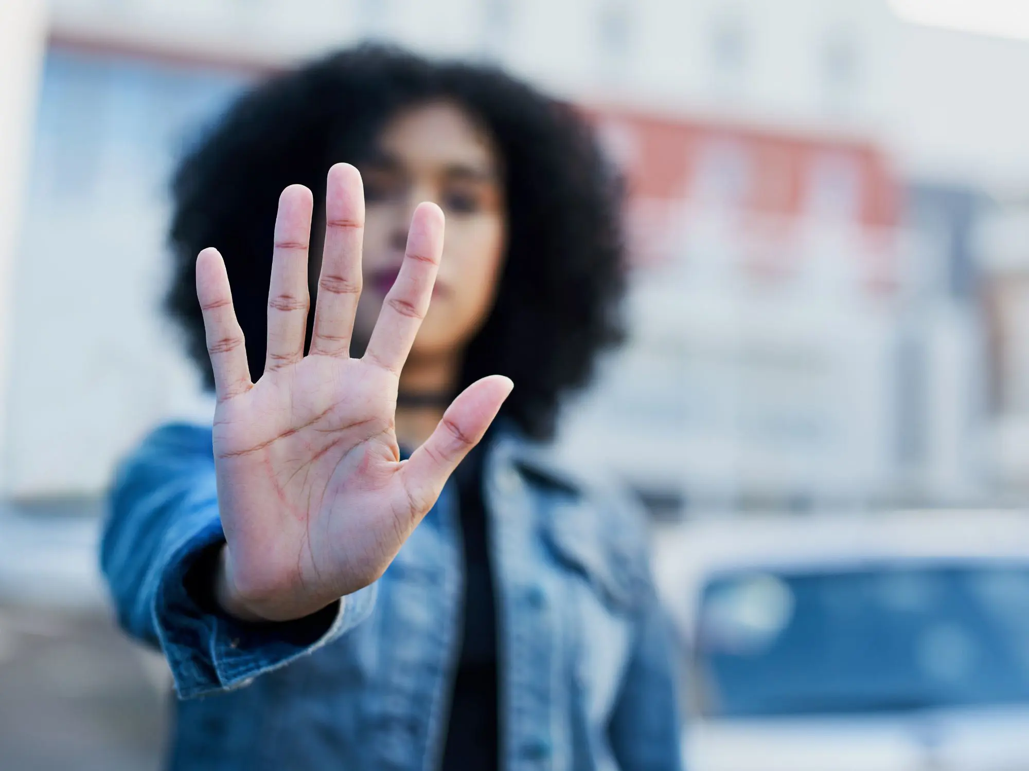 Person holding up an open hand in a “stop” gesture, symbolising a stand against hate crime and promoting respect and safety in the community.