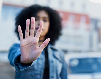 Person holding up an open hand in a “stop” gesture, symbolising a stand against hate crime and promoting respect and safety in the community.