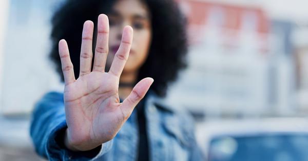 Person holding up an open hand in a “stop” gesture, symbolising a stand against hate crime and promoting respect and safety in the community.