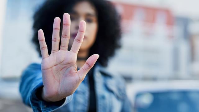 Person holding up an open hand in a “stop” gesture, symbolising a stand against hate crime and promoting respect and safety in the community.