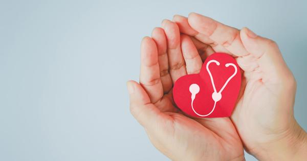 Hands gently holding a red heart-shaped object with a white stethoscope design, set against a light blue background.