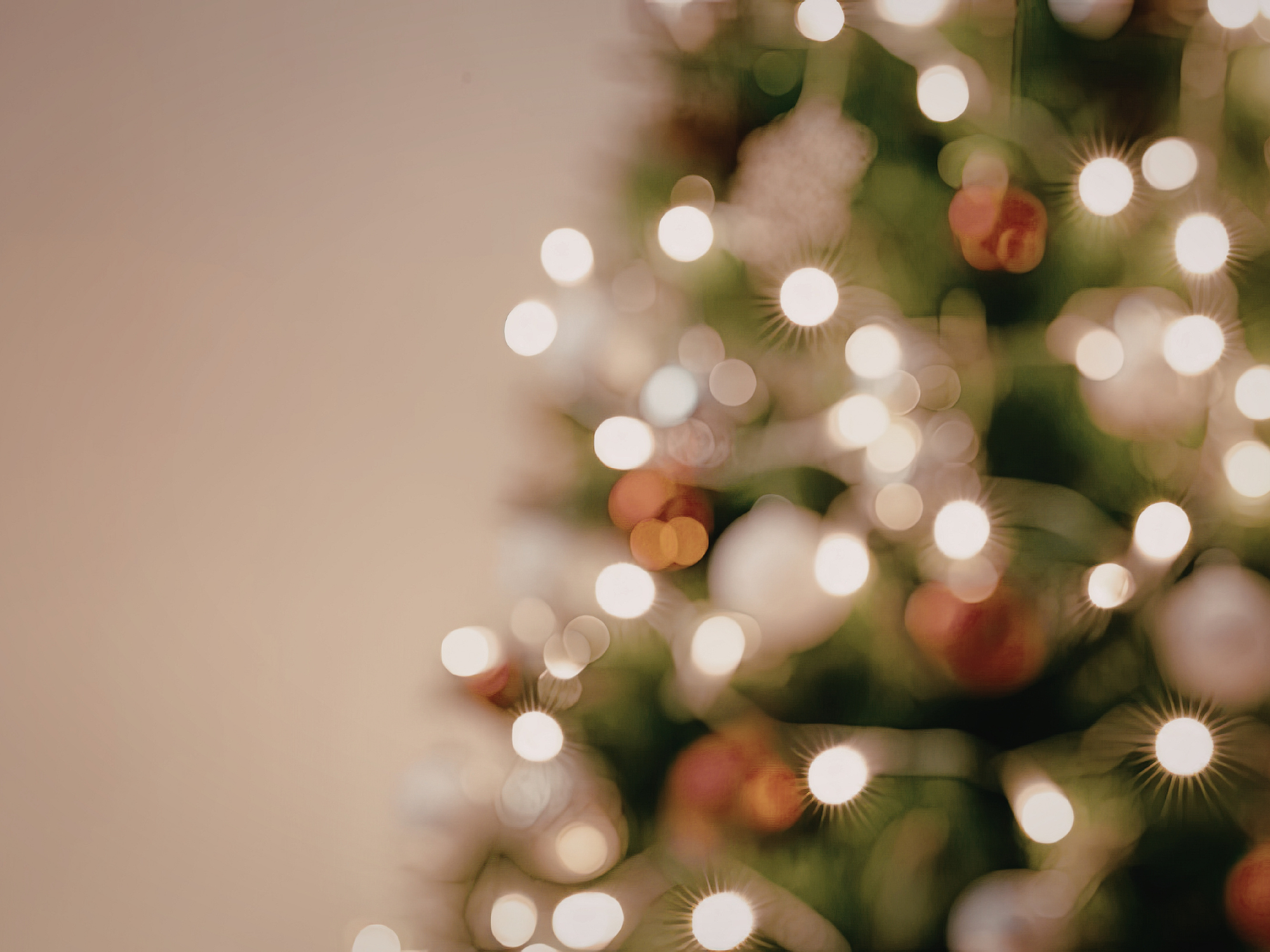 Out-of-focus Christmas tree decorated with warm white lights and red, silver and white baubles.