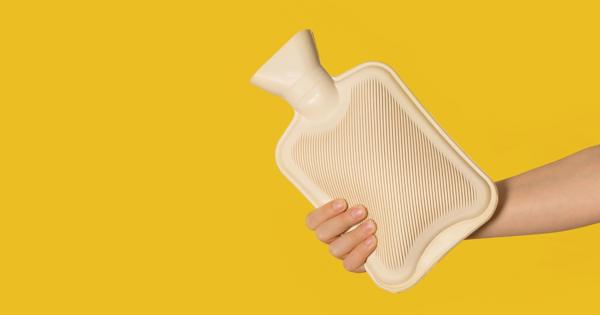 A hand holding a beige ribbed hot water bottle against a solid yellow background.