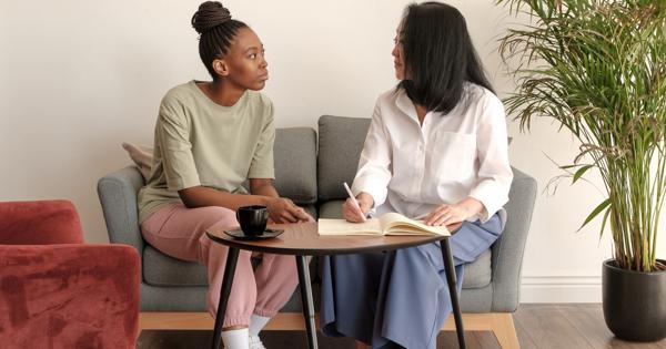 Two people seated on a couch in conversation, with one writing in a notebook, symbolising support and dialogue for witnesses and perpetrators of anti-social behaviour.