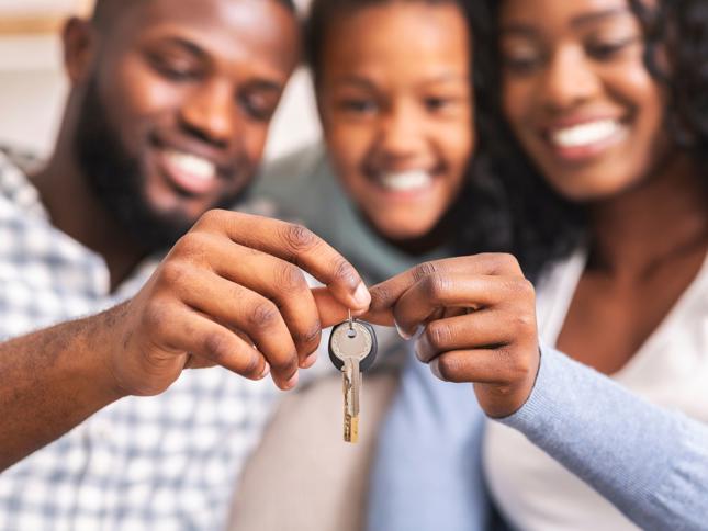 Close-up of two people holding a house key together, symbolising moving into a new home. Close-up of two people holding a house key together, symbolising moving into a new home.