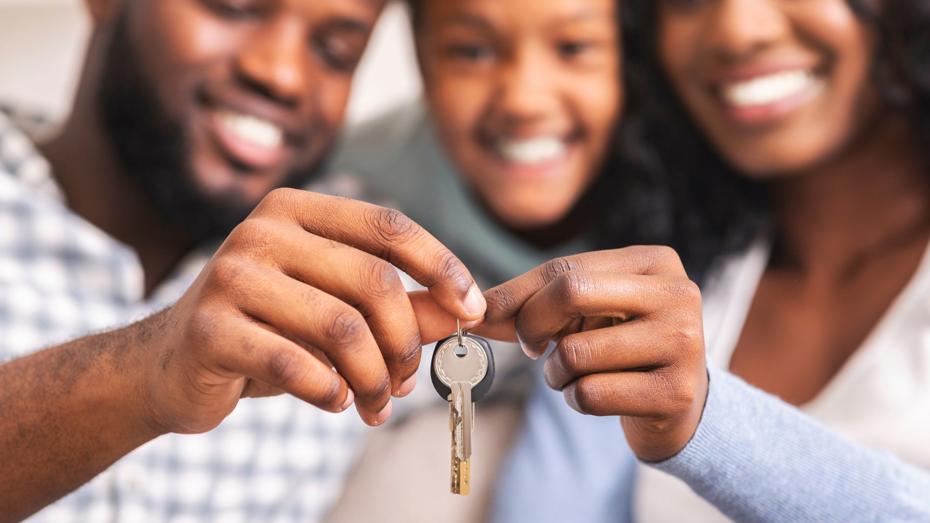 Close-up of two people holding a house key together, symbolising moving into a new home. Close-up of two people holding a house key together, symbolising moving into a new home.
